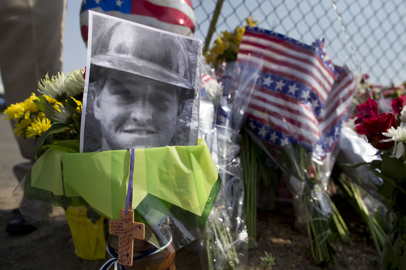 A photo of one of the 19 Granite Mountain Hotshot crew members who were killed fighting a wildfire near Yarnell, Ariz., on Sunday, sits at a makeshift memorial outside the crew's fire station on Monday in Prescott, Ariz.