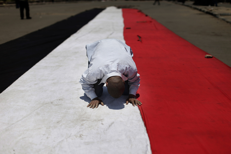 A supporter of ousted Egyptian President Mohammed Morsi prays on an Egyptian flag during the Friday prayer before a protest near the University of Cairo in Giza, Egypt.