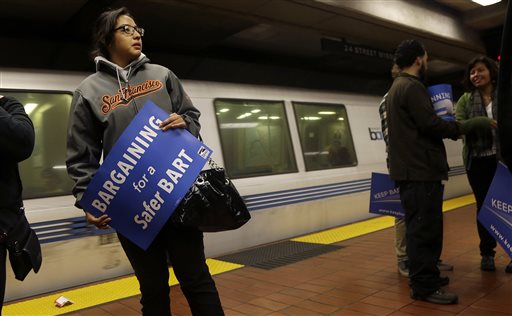 FILE - In this Tuesday, June 25, 2013 file photo, Jeanette Sanchez holds a sign supporting Bay Area Rapid Transit workers as she waits for a train at the 24th Street Mission station in San Francisco. Early Monday, July 1, 2013, two of San Francisco Bay Area Rapid Transit's largest unions went on strike after weekend talks with management failed to produce a new contract. (AP Photo/Jeff Chiu)
