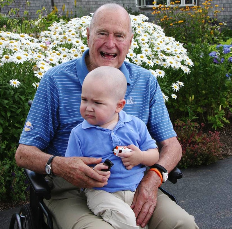 Former President George H. W. Bush sits with Patrick, 2, whose last name was withheld at the family's request, in Kennebunkport on Wednesday. Bush joined members of his Secret Service detail in shaving his head to show solidarity with Patrick, who is undergoing treatment for leukemia and is losing his hair as a result.