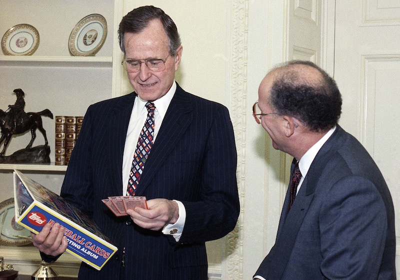 In this Feb. 5, 1990 file photo, President George H.W. Bush jokes with Arthur Shorin, President of Topps, Co., Inc., after Shorin presented him a book of baseball cards during a meeting in the Oval Office in Washington. Baseball cards depicting the former president as a Yale first baseman have fetched thousands of dollars each since they were specially-made for the White House in 1990. But Joe Orlando, president of Professional Sports Authenticator in Santa Ana, Calif., said Tuesday, July 9, 2013, that many of the Bush cards in circulation were not part of the set presented to the president.