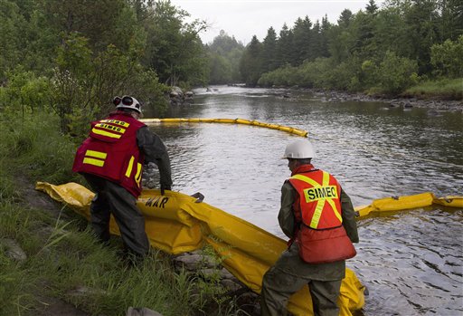 Workers lay booms on the Chaudiere River near Lac-Megantic, Quebec, to contain the crude oil spill following a train derailment and explosion.