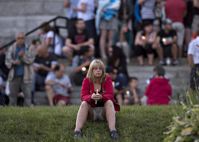 A women sits in front of the St-Agnes church during a vigil to the victims of the train crash in Lac-Megantic, Quebec, Friday, July 12, 2013. Transportation workers moved carefully Friday in and around the site of the nearly week-old derailment that incinerated the heart of this small Quebec town and killed 50 people, searching for evidence that would help explain what led to such massive destruction. (AP Photo/The Canadian Press, Jacques Boissinot) Canada;Quebec;Montreal;transportation;business;Canadian;economic;economy;industry;move;ship;shipping;transit;transport;travel industry;commerce;tourism;fire;train;rail;derail;tragedy;disaster