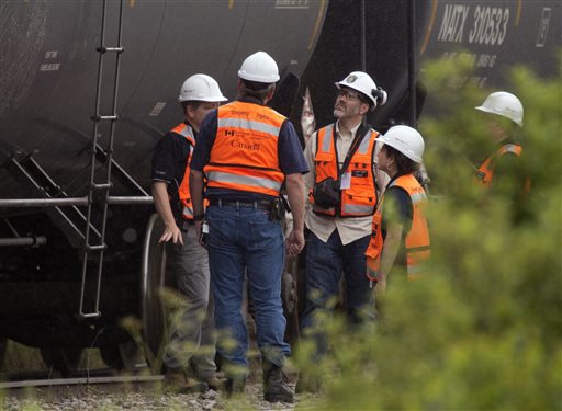 Environment Canada emergency inspectors check on nine MM&A tanker cars that remain on the tracks in Nantes, Quebec, Wednesday. A train engineer reportedly rushed to borrow a tractor from an area forestry company; grabbed a fireman's suit from an area department; and pushed nine fuel-filled cars weighing 100 tons away from the explosive danger on the night of the derailment, according to the company.