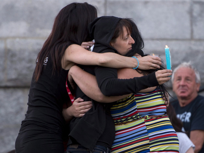 People comfort each other in front of the St-Agnes church during a vigil for the victims of the train crash in Lac-Megantic, Quebec, on July 12. Police raided the railway's Canadian office in a search for evidence Thursday, July 25, 2013.