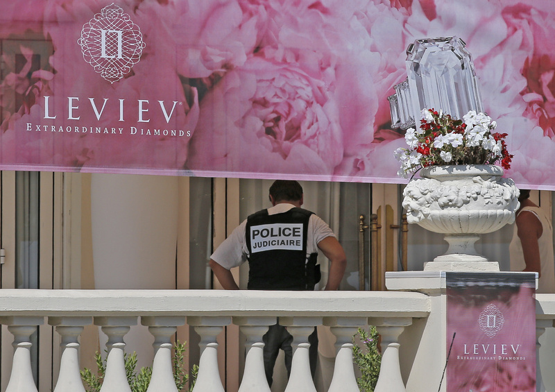 A police officer stands in front of the Carlton Intercontinental Hotel in Cannes, southern France, where $53 million worth of jewels was stolen Sunday.
