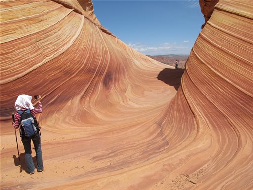 This May 28, 2013, photo shows a hiker taking a photo on a rock formation known as The Wave in the Vermilion Cliffs National Monument in Arizona. The flowing sandstone rock formation near the Utah-Arizona border that claimed the lives of a California couple earlier this month.