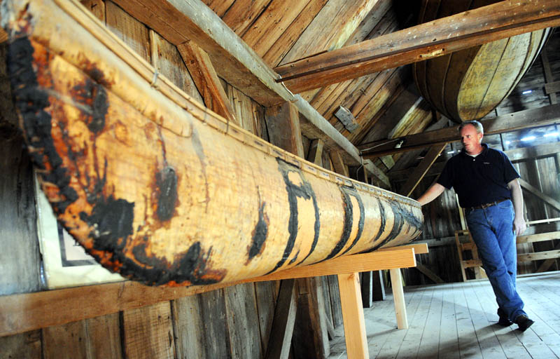 Tom Desjardin, historian with the state department of agriculture's Division of Parks and Lands, inspects a 18th Century birch bark canoe built by Native Americans, on display at the Colburn House State Historic Site in Pittston on June 25. The Kennebec Historical Society will hold a program at the house, built in 1765, on Saturday, July 13, that features a collection of boats in the barn.