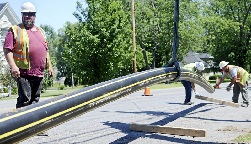 Dan McGee, left, and Randy Sidelinger of McGee Construction move a natural gas pipeline Monday with Jake Chavez of Tetra Tech Construction in Gardiner. Both firms are working for Summit Natural Gas of Maine on installing a distribution line through Kennebec County.