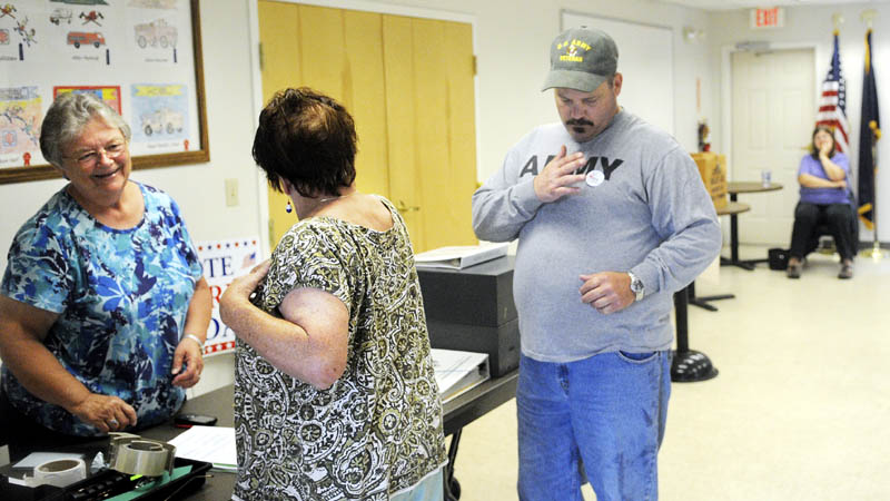 Jefferson deputy town clerk Brenda Williams, left, confers with Cindy Hennessey as she applies an "I Voted" sticker, after casting a ballot today with her son, Dan, right, on the school budget. At far right is voting clerk Cheryle Fasano.