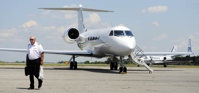A pilot walks past two private jets July 16 near Maine Instrument Flight at the Augusta State Airport. Maine Instrument Flight owner William Perry said more jets are arriving earlier to visit summer campers than previous years. "It's not a weekend anymore," Perry said of the arrival of dozens of private planes in Augusta, which his company services. He expects several dozen flights this weekend.