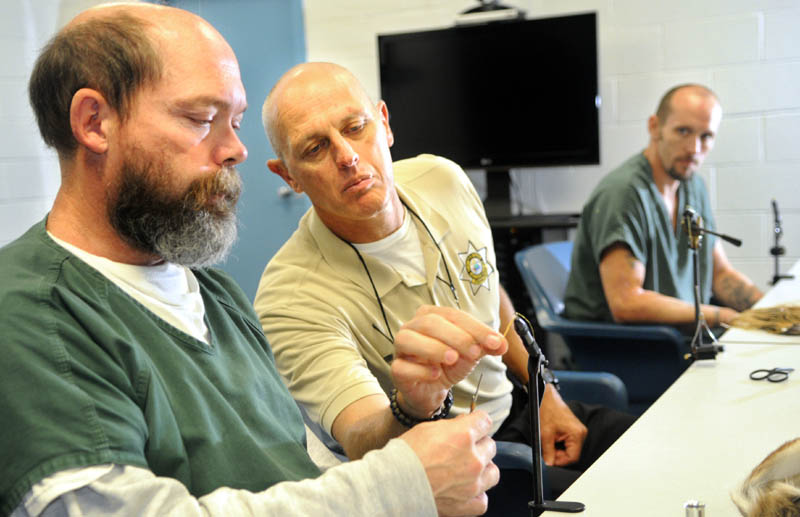 Inmates Chris Ring, left, and Jared Small, right, learn to tie fishing flies with corrections Sgt. Alan Gregory Tuesday, in a conference room at the Kennebec Country Correctional Facility in Augusta. The veterans are serving time together on the same cell block. A fly-fishing guide and veteran, Gregory said the men are being taught to tie the flies to learn a new skill that may earn them money.