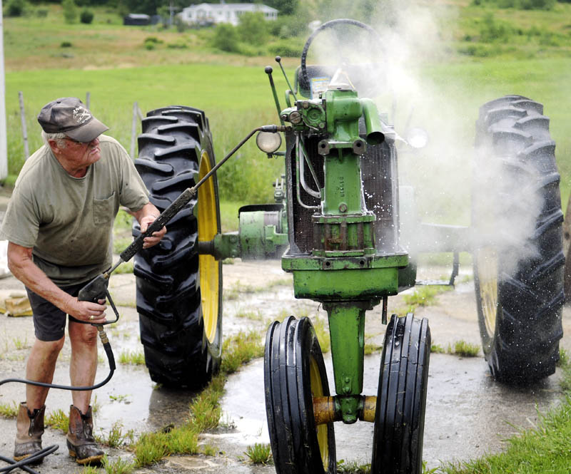 Jim Norton steam cleans a 1955 John Deere tractor Monday he's rebuilding at his Farmingdale farm. "Just giving her a bath," Norton said of restoring the antique implement, while waiting for the hay to dry for the first cut of the season.