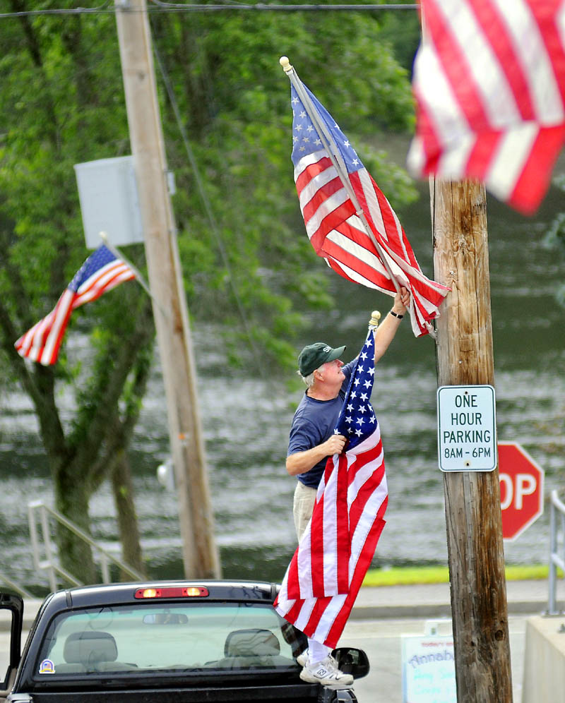 Bob Hurley replaces a flag Wednesday on Main Street in Richmond. Hurley and Tom Sullivan of American Legion Post 132 cruised through town updating the summer pennants on display ahead of Richmond Days this weekend.