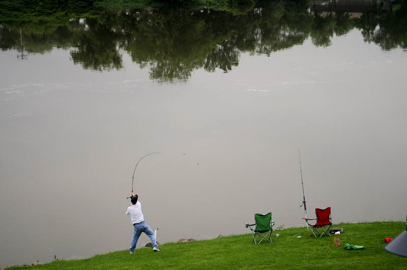 Jason Silver, of Gardiner, casts a line Monday into the Kennebec River in Gardiner. Despite high water from recent rain, several anglers fished for striped bass from the banks of the river, which was permitted beginning July 1.