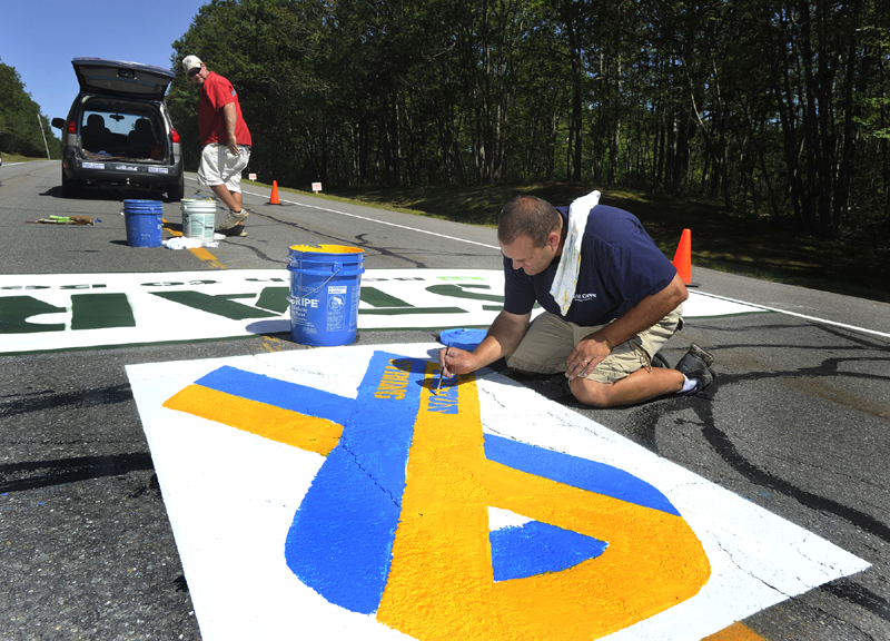Matt Tobin and Jeremy Gardner paint the starting line on Route 77 in Cape Elizabeth in advance of the upcoming Beach to Beacon road race. Tobin, an employee of Pioneer Athletics, put the finishing touches on painted Boston Strong ribbon in memory of this year's Boston Marathon tragedy.