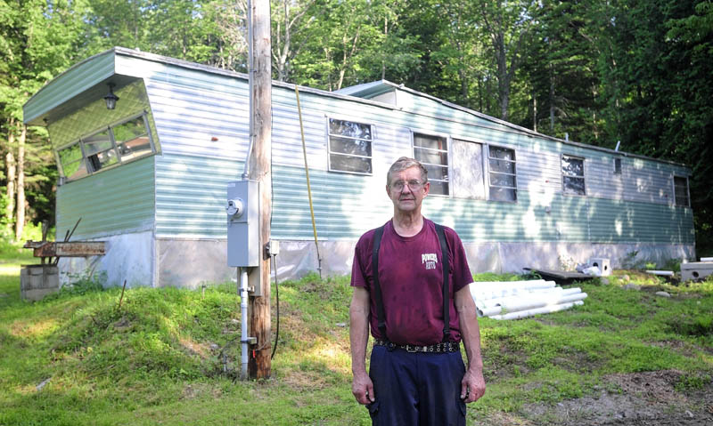 Cliff Risinger stands outside his circa 1978 trailer, at 88 Norridgewock Road in Fairfield on Tuesday. Risinger is applying for a grant that will allow him to fix up his home.