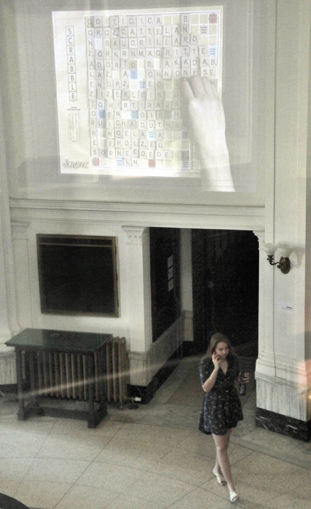 A Maine International Film Festival-goer enters the lobby of the old post office in downtown Waterville on Saturday, as Alejandro Cesarco's "Scrabble" is projected on the wall as part of the MiffOnEdge presentation.