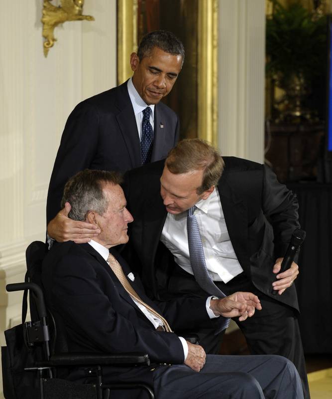 President Barack Obama, standing, watches as former President George H. W. Bush, left, gets a hug from his son Neil Bush during a ceremony to recognize the 5,000th Daily Point of Light Award at the White House on Monday.