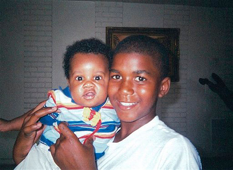 In this undated photo provided by the Martin family, Trayvon Martin holds an unidentified baby. A jury began deliberating George Zimmerman's fate Friday, July 12, 2013 after hearing dueling portraits of the neighborhood watch captain: a cop wannabe who took the law into his own hands or a well-meaning volunteer who shot Trayvon Martin because he feared for his life. (AP Photo/Martin Family, File)