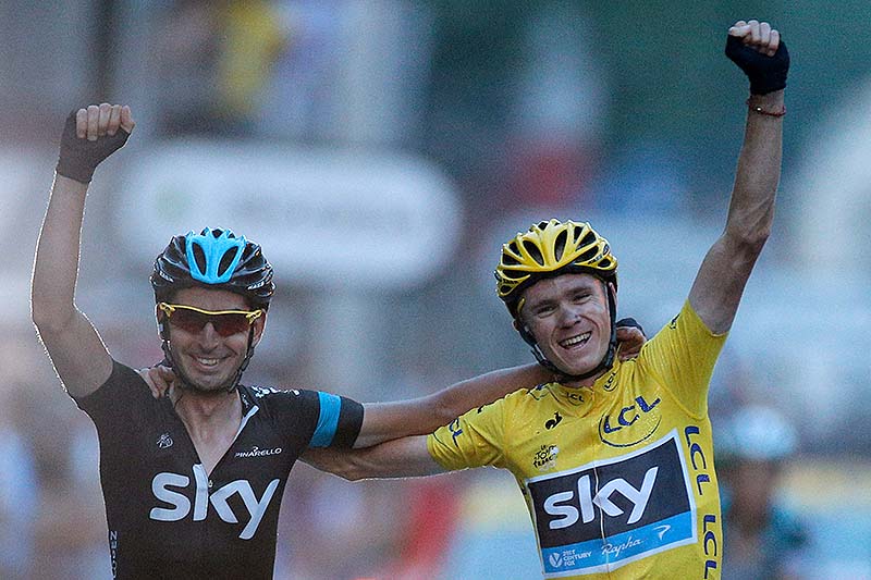 Chris Froome, wearing the overall leader's yellow jersey, crosses the finish line with a teammate in the last stage of the 100th edition of the Tour de France.