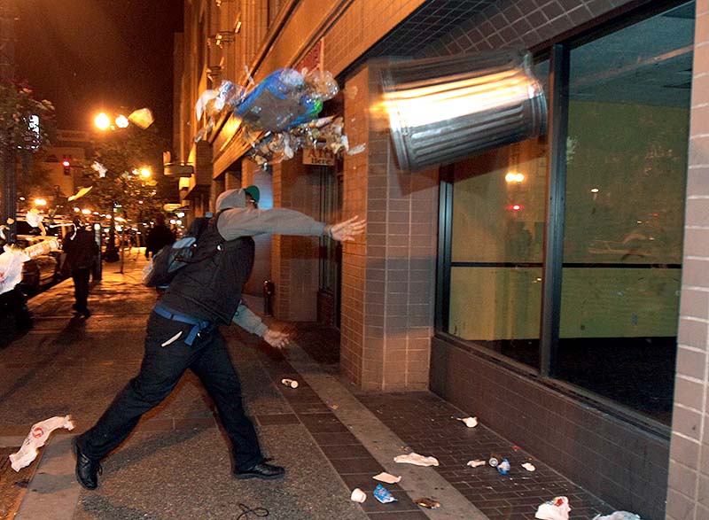 A man throws a trash can at the window of a building during a protest after George Zimmerman was found not guilty in the 2012 shooting death of teenager Trayvon Martin, early Sunday in Oakland, Calif. Protesters angered by the acquittal Zimmerman held largely peaceful demonstrations in three California cities, but broke windows and started small street fires Oakland, police said. ANDACHU 2013 EASTBAY southbay Protesters march in Oakland vandal