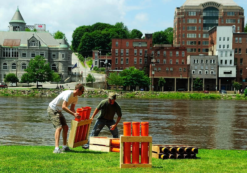 John Posey, left, and Chris Henderson stack fiberglass launch tubes on Thursday at the Eastside Boat Landing in Augusta. The crew from Central Maine Pyrotechnics started setting up for the 9:15 p.m. show around noon.