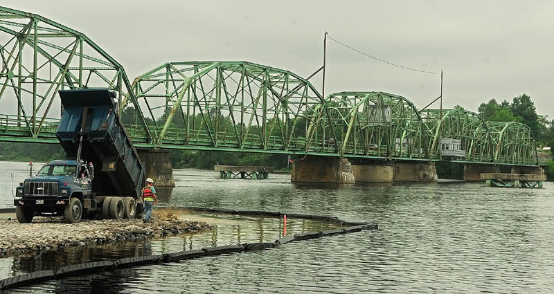 Reed & Reed Construction workers build a construction causeway on the Kennebec River Wednesday.