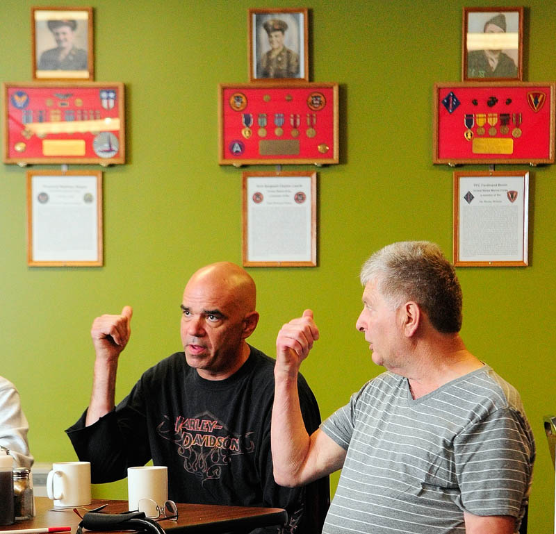 Thomas "TJ" Quinn, left, and Larry Day gesture towardsthe memorial wall display during an interview on Tuesday at TJ's Place, on Route 202 in Monmouth.
