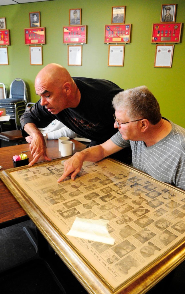 Thomas "TJ" Quinn, left, and Larry Day look at framed newspaper pages showing all the local people killed in World War II, during an interview on Tuesday at TJ's Place, on Route 202 in Monmouth.