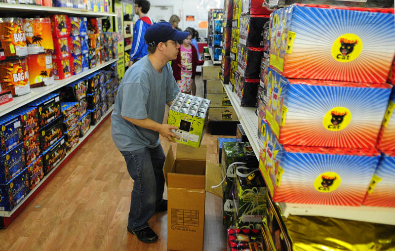 Brandon Pelletier restocks shelves on Tuesday at the Pyro City fireworks store on Route 202 in Manchester. Store manager Jeremy Mitchell said that they'd seen an increase in shoppers over the last two weeks.