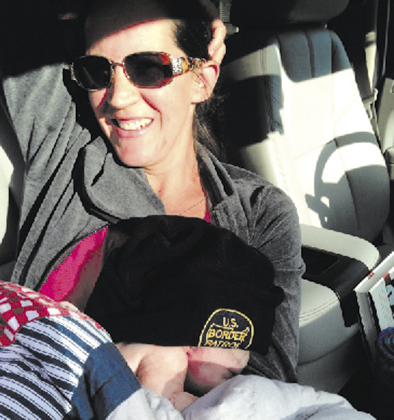 Jill Demanski holds her son, Michael, after giving birth with help from her husband, Chris, in a driveway along Route 104 in Fairfield this morning. The baby is wearing a U.S. Border Patrol hat owned by his father, Chris, who works as an agent for the agency.