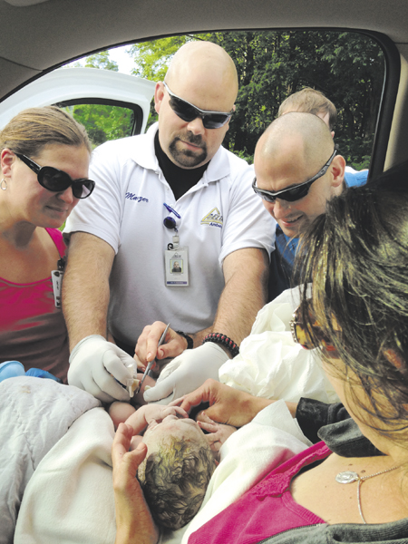 Delta Ambulance paramedic Jeremy Manzer, center, checks on baby Michael, who was delivered in the back seat of a car in Fairfield this morning. The parents, Jill and Chris Demanski, of Jackman, were driving to Inland Hospital in Waterville but had to pull over into a stranger's driveway, where the baby was delivered at 7:35 a.m.