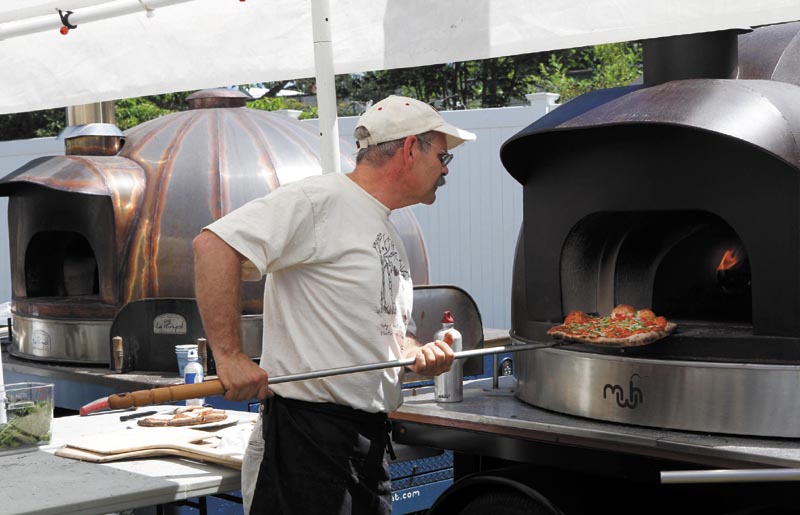 Andy Davis, of Solon, checks on a pizza while baking it in a wood-fired oven during the annual Kneading Conference and Artisan Bread Fair, at the Skowhegan State Fairgrounds, on Saturday. Davis was volunteering at the pizza stand, run by the Maine Grain Alliance. The Le Panyol wood-fired ovens he and fellow volunteers were using were made in Skowhegan by Maine Wood Heat Co. Inc.