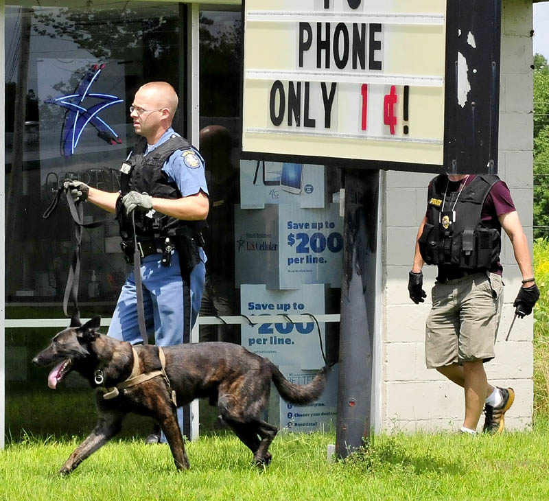 Maine State Police Trooper Scott Dalton, with a tracking dog, and Waterville police officer Bill Bonney search the area off the Armory Road in Waterville after the report that a Little Caesar's restaurant was robbed this afternoon.