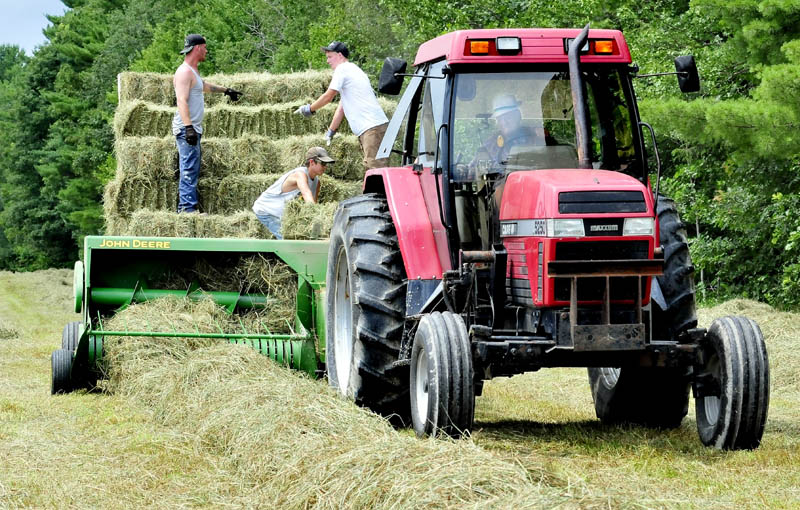 Charlie Kent, of Benton, drives his tractor as workers stack bales of hay while scrambling to get the crop in on Monday, before the next two days of rain. Kent said his hay crop is behind this year due to the weather. "Too much rain in the spring and not enough time to dry cut hay this summer," Kent said.