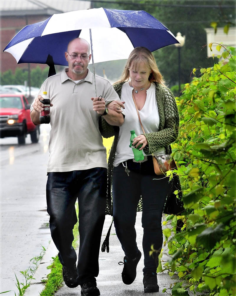 Danny Velez and Hope Stenson sip sodas while walking together under an umbrella during rain on Tuesday. "This rain doesn't bother us," Stenson said.