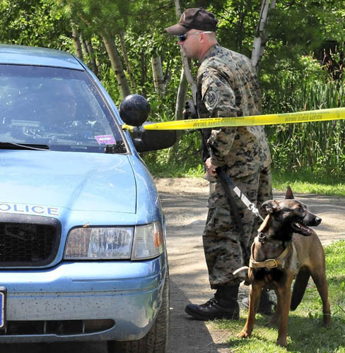 A state police trooper and dog prepare to search the grounds of a mobile home at 24 Main Street in Detroit after a deceased male was found earlier Thursday.