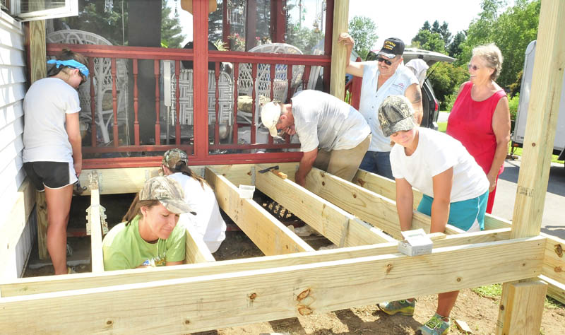 North Anson residents Robert and Carrol Thompson, at right, watch as the group Mission of the Eastward builds a porch on their home on Tuesday. From left, Lauren Kane, Emily Kelley, Allie Hoffman, Dennis Painter and Lauren Logan work on the structure.