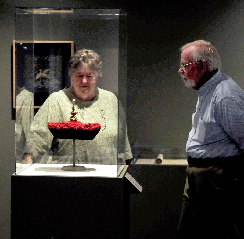 Faye and Jim Nicholson look over the "Winter Court Hat" on display at the Colby College Museum of Art.