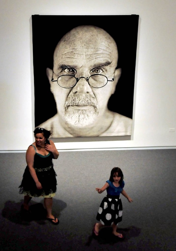 Mary Bedard, left, and Emma Alley walk past a self portrait tapestry by Chuck Close during one of many tours at the Colby College Museum of Art in Waterville on Sunday. The event was part of the museum Community Day.