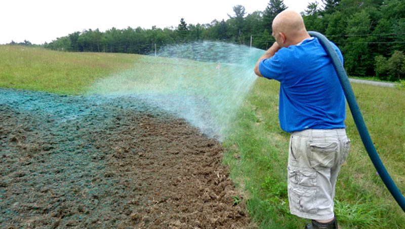 Norm Vigue, of Central Maine Hydroseeding, an Oakland-based firm that has donated its services, sprays a cover of wood fiber mulch, fertilizer and water onto the ground to protect newly planted wildflower seeds. The seeds, which were planted by Oakland transfer station Manager John Thomas, are part of a trial experiment in Thomas' efforts to transform the capped landfill into a feeding station for hummingbirds and migrating monarch butterflies.