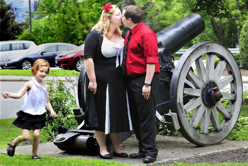 Newlyweds Erica and David Tompkins kiss beside a cannon in Castonguay Square in Waterville, moments after they were married in a civil ceremony, on Monday. Their daughter, Christina, runs around the couple as family members take photographs.