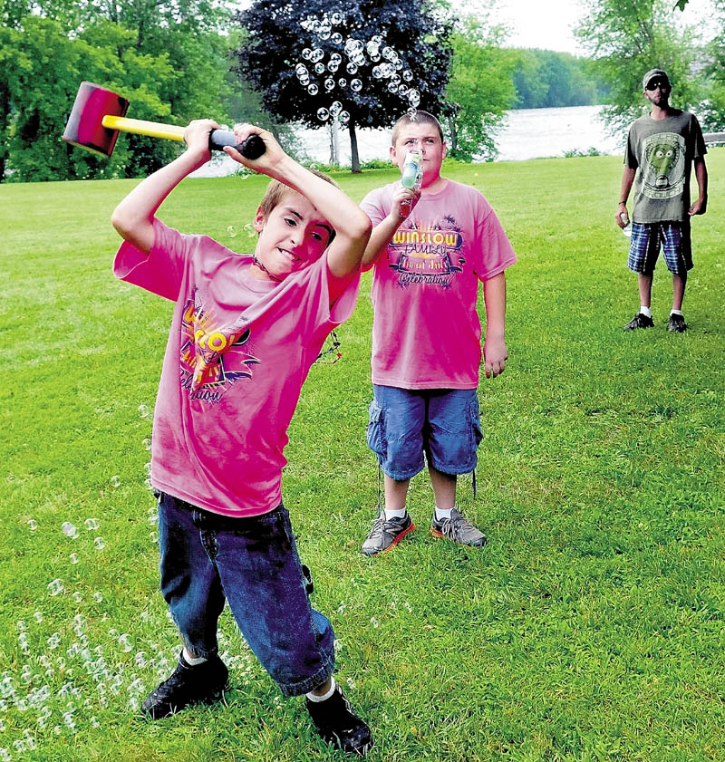 Hunter Desveaux swings a hammer to ring the bell on a game, as Gage Vaughan provides the bubbles, at Fort Halifax during the Winslow Family Fourth of July celebration on Monday. Live bands provided music and folks enjoyed a bean supper meal all day.