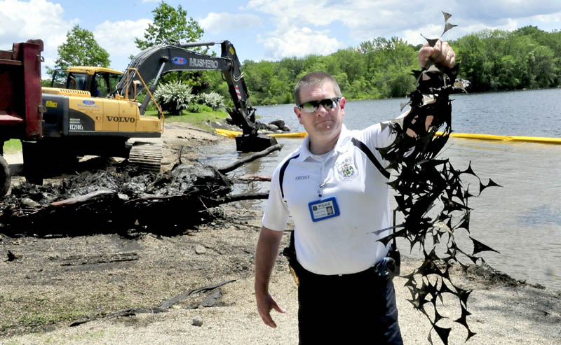 Oakland police Detective Tracey Frost holds up some metal that was dredged from the bottom of Messalonskee Lake at the boat landing on June 17. The cost of removing scrap metal from around the area of the town boat landing exceeded Oakland's estimates, but the town hopes to recoup much of that cost by selling off the salvaged metal.
