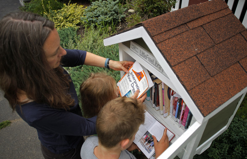 Julie Falatko and her children, 3-year-old Ramona and 7-year-old Eli, rearrange books in their Little Free Library in front of their South Portland home.