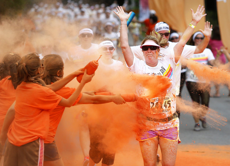 Participants are doused in orange-tinted cornstarch during The Color Run in South Portland earlier this month. It is one of several in Maine this year being put on by for-profit companies, reflecting a national trend. Some worry that the fun runs will compete for participants with traditional local road races.