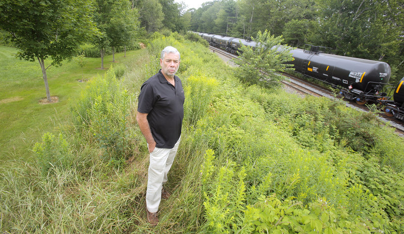 Bill Vinson is concerned about the frequency that tanker cars are being parked on a railroad siding next to his property in Scarborough. Vinson is photographed Monday, July 22, 2013 atop a berm between his backyard, at left, and the railroad tracks and siding.