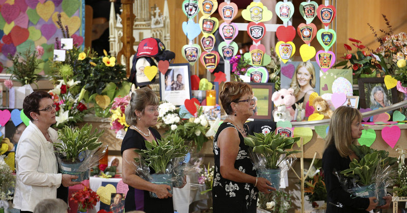 People proceed past a memorial during a ceremony at the Ste.-Agnes church in Lac Megantic, Quebec, on Saturday.