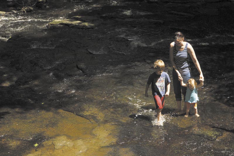 Lissa Niederer, of Augusta, her 20-month-old daughter, Kinsey, and 6-year-old son, Sam, cool their feet in a stream at Vaughan Woods in Hallowell on Friday. After a cloudy, wet start to the week, the weekend is expected to be hot, dry and perfect for outdoor activities.